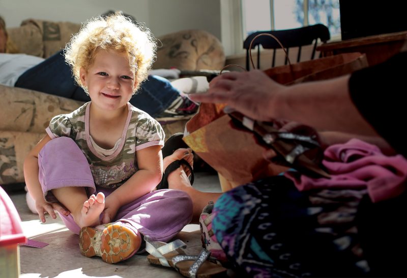 Liliana, almost age 3, practices putting on shoes during a visit with a home visitor from TLC Family Resource Center. (Photo by Cheryl Senter).