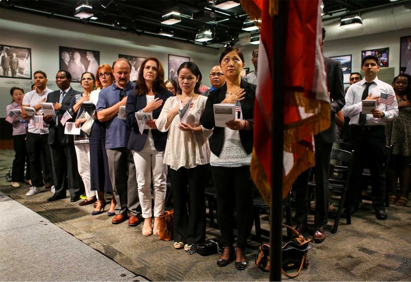Hong Mei Zhai, of Derry, facing center, says the Pledge of Allegiance with others during a citizenship ceremony held at St. Anselm’s Institute of Politics. (Photo by Cheryl Senter.)
