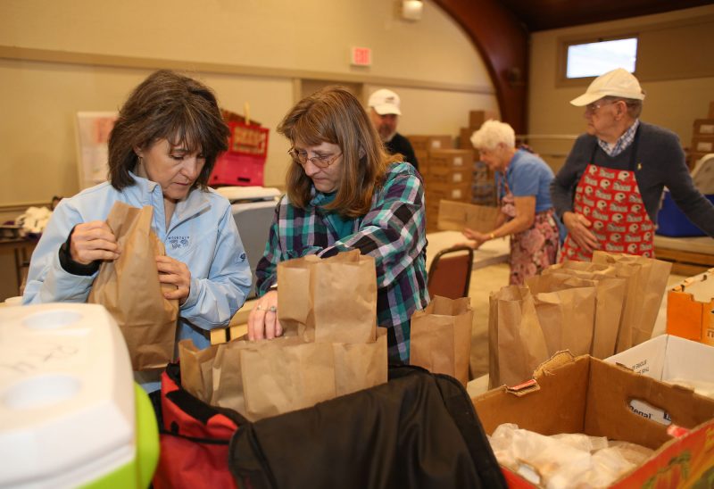 Volunteers help prepare meals for Meals-on-Wheels delivery.