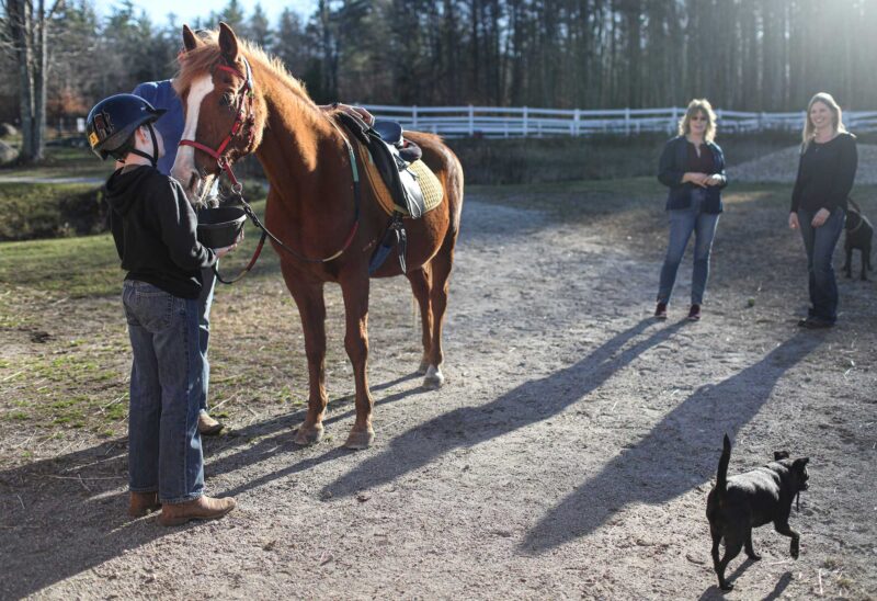 Ty, a 13-year-old from Hopkinton who was enrolled in the program, with his mom and Back in the Saddle Equine Therapy Center Executive Director Jaryn Hall-Haines. (Photo by Cheryl Senter.)