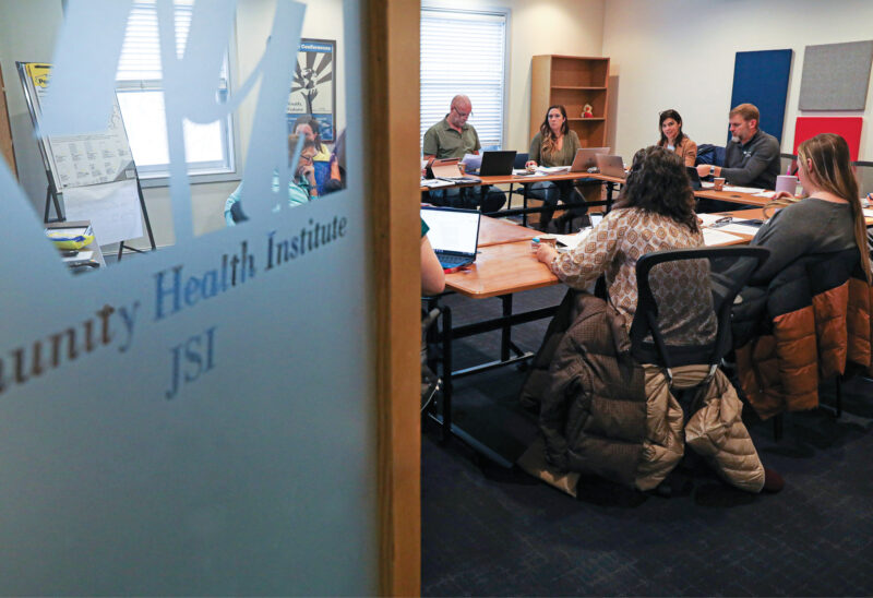 A group of people having a meeting at a table as seen through a partially opened door